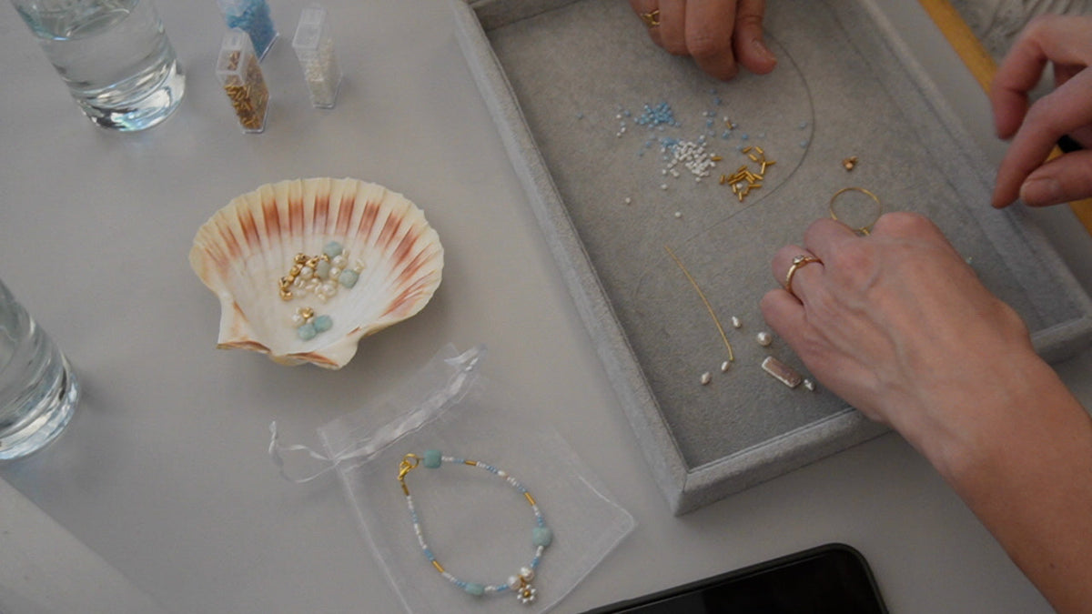 Nærbillede af smykkefremstilling under firmaarrangement med Smyk&Hyg, hvor deltagere designer armbånd med perler og materialer som en kreativ teambuilding aktivitet ud af huset i Vejle.