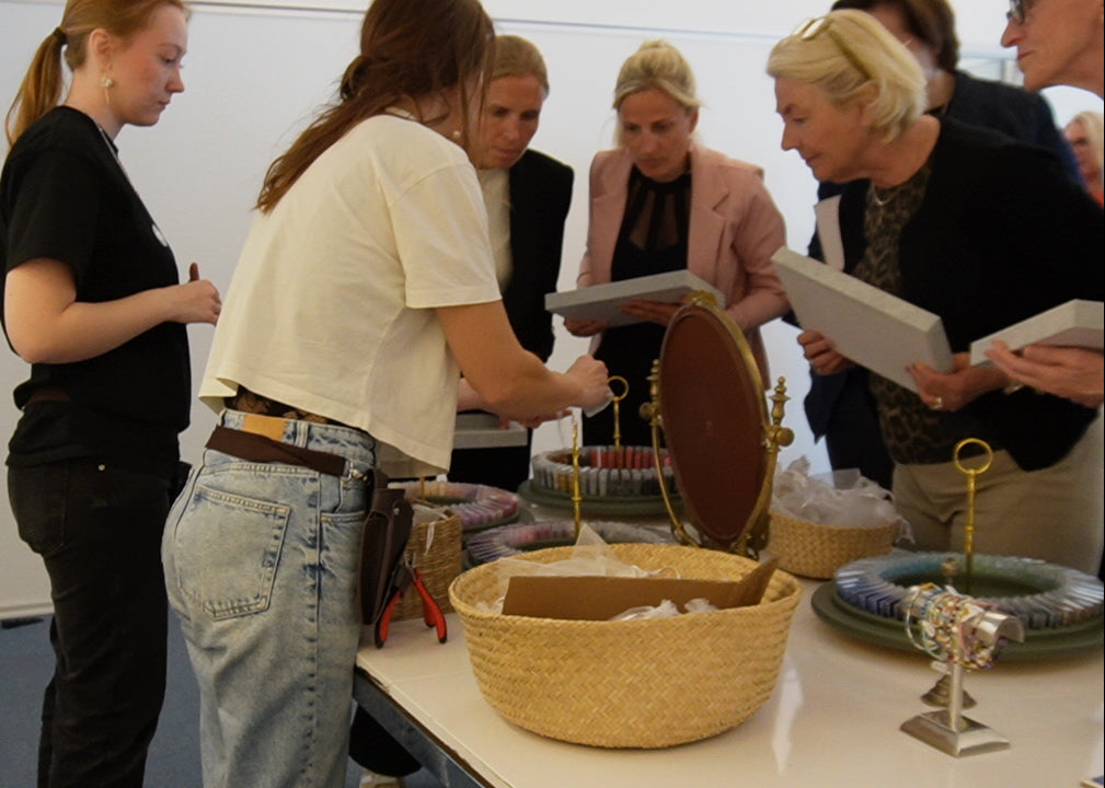 Deltagere til firmaarrangement samles omkring materialer og smykkedele under en kreativ smykkeworkshop ud af huset med Smyk&Hyg – en teambuilding aktivitet for virksomheder i Vejle.