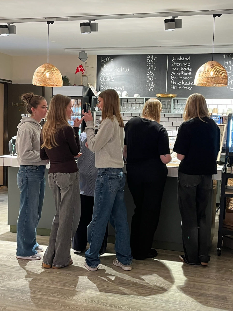 En gruppe veninder står ved desken hos Smyk og Hyg og snakker om, hvilke perler, de skal vælge.