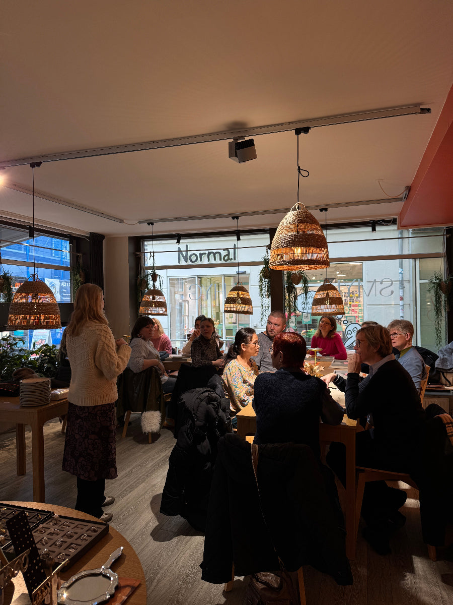 Deltagere til virksomhedsevent hos Smyk&Hyg i Vejle sidder samlet ved borde og laver smykker i hyggelige omgivelser med fokus på kreativitet, samarbejde og teambuilding